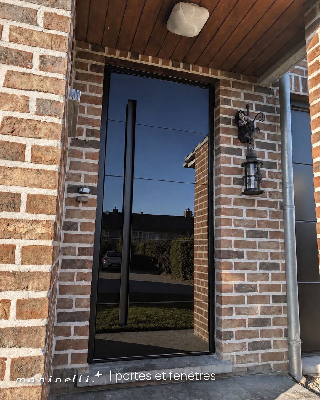 Porte d'entrée moderne noire avec habillage en verre effet miroir — maison à Beaufays